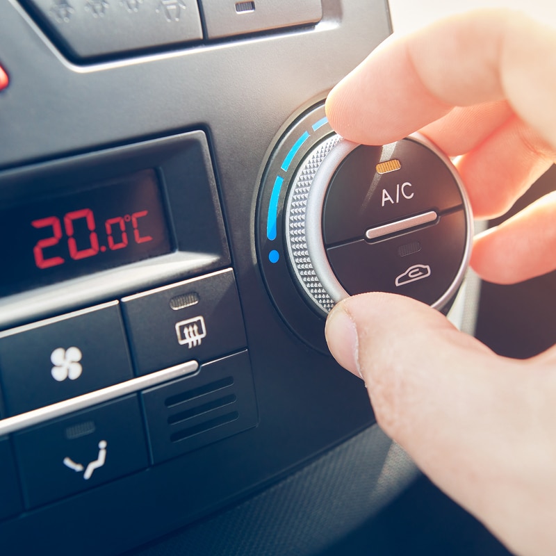 Main ajustant le bouton de climatisation automobile à 20.0°C, réglant la température et activant l'A/C.
